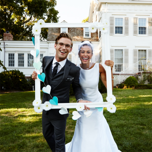Bride and groom posing with homemade life-size photo frame.